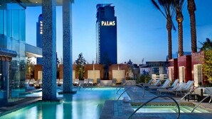 A hotel pool area with lounge chairs, a tall building labeled 'PALMS' in the background, and palm trees. - SVS: Strip View Studio | Open Balcony | Resort Pool | Palms Place (Las Vegas)