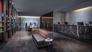 Una hall moderna con reception, area salotto e parete in vetro.