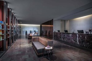 Eine moderne Lobby mit einer Rezeption, einer Sitzecke und einer Glaswand.