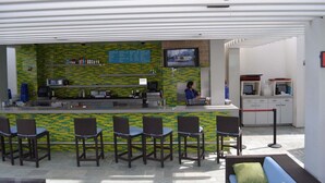 A bar area with a counter, chairs, a TV screen, and a menu board. - Palms Place Studio, Strip Views & Balcony Options (Las Vegas)