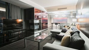En moderne stue med et fladskærms-tv, et glasbord, en sofa og et spiseområde med bord og stole.