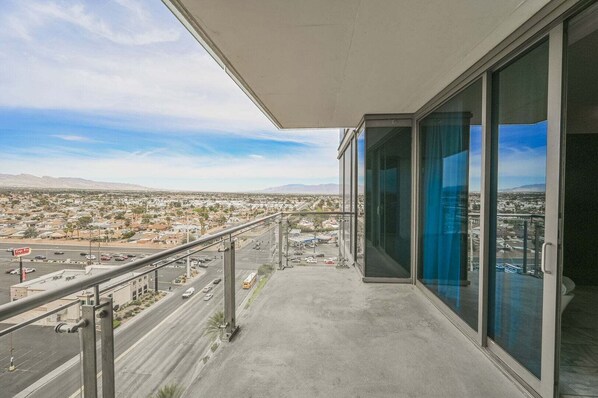 Un balcone con vista sulla città, cielo sereno e catena montuosa in lontananza.