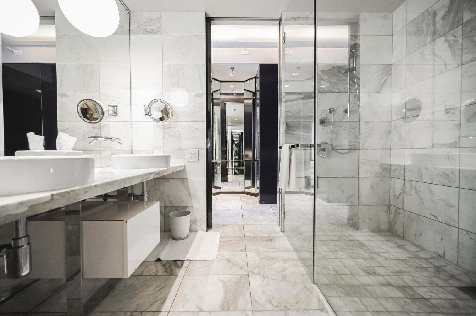 Un baño moderno con cabina de ducha de vidrio, un espejo grande y un tocador con lavabo y perchero para toallas.