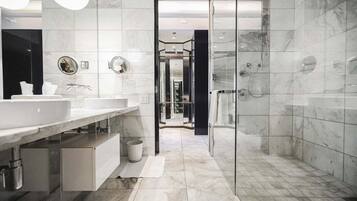 Un baño moderno con cabina de ducha de vidrio, un espejo grande y un tocador con lavabo y perchero para toallas.