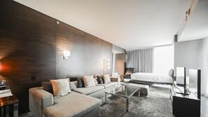 A modern hotel room with a sofa, a coffee table, a bed, a TV, and a desk with a lamp. - SVS: 1BD Strip View | Jetted Tub | Full Kitchen | Sleeps 6 | Palms Place (Las Vegas)