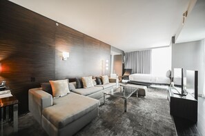 A modern hotel room with a sofa, a coffee table, a bed, a TV, and a desk with a lamp. - SVS: 1BD Strip View | Jetted Tub | Full Kitchen | Sleeps 6 | Palms Place (Las Vegas)