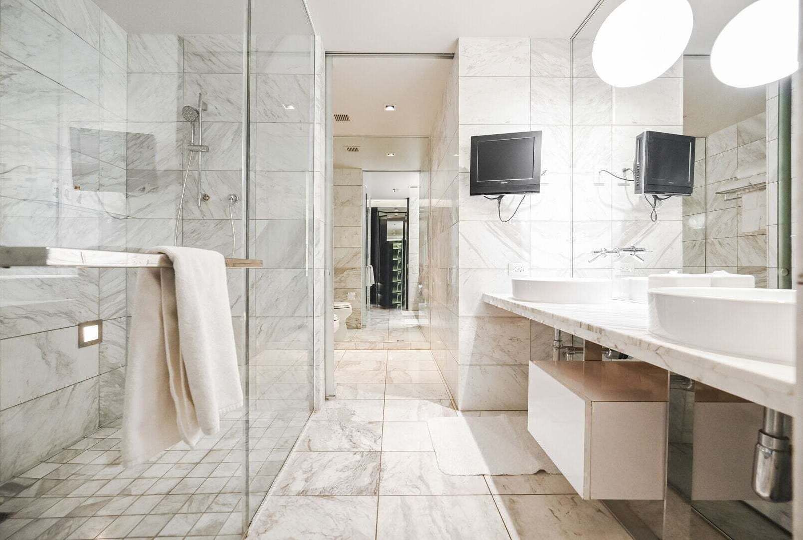 A modern bathroom with a glass-enclosed shower, two sinks, and a large mirror.