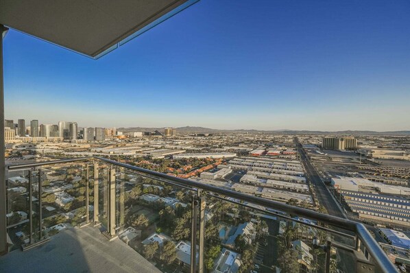 Vista urbana com edifícios altos, céu claro e um terraço com guarda-corpo.