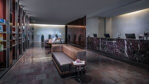 A modern reception area with a marble counter, seating, and a glass wall with a logo. - SVS: High Floor 1BD | Full Kitchen | Jetted Tub | Sleeps 4 | Palms Place (Las Vegas)