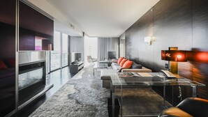 A modern hotel room with a large window, a flat-screen TV, a sofa with red cushions, a glass coffee table, and a desk with a telephone. - SVS: High Floor 1BD | Full Kitchen | Jetted Tub | Sleeps 4 | Palms Place (Las Vegas)