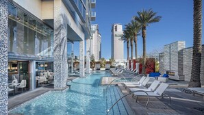 A hotel pool area with lounge chairs, a bar, and a tall building labeled 'PALMS' in the background. - SVS: High Floor 1BD | Full Kitchen | Jetted Tub | Sleeps 4 | Palms Place (Las Vegas)