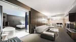 Ein modernes Hotelzimmer mit einem großen Bett, einer Sitzecke, einem Essbereich, einem Fernseher und einem Badezimmer.