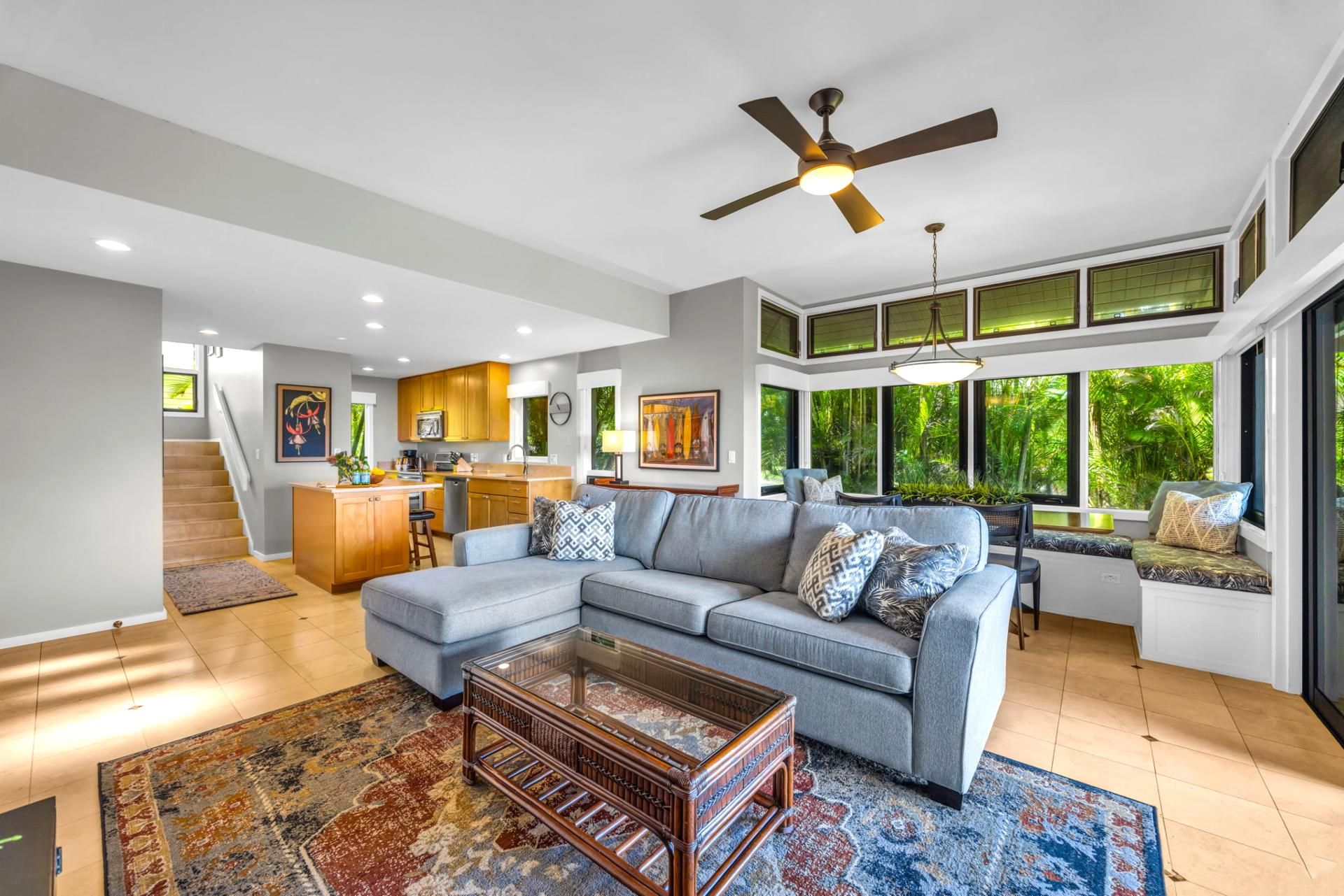 A modern living room with a sectional sofa, a coffee table, and a staircase leading to an upper level.