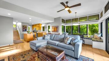 A modern living room with a sectional sofa, a coffee table, and a staircase leading to an upper level.
