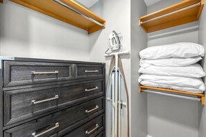 A bathroom with a dark wooden cabinet, a towel rack, and a shelf with folded towels.