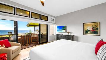 Ein Schlafzimmer mit einem großen Bett, Meerblick, einem Balkon mit Stühlen und einem Deckenventilator.