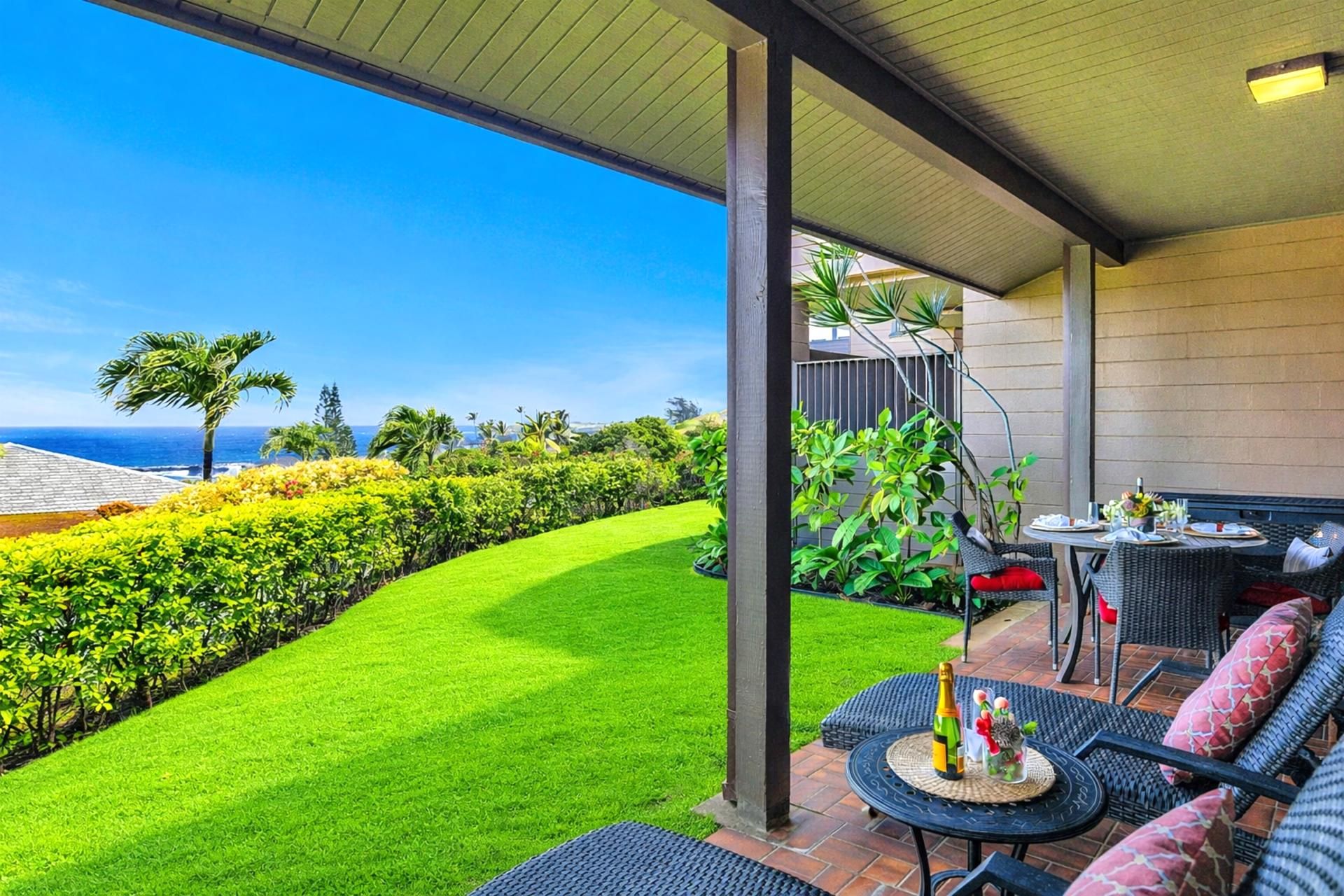 Eine Terrasse mit Sitzgelegenheiten im Freien, Blick auf den Ozean und gepflegtem Grün.