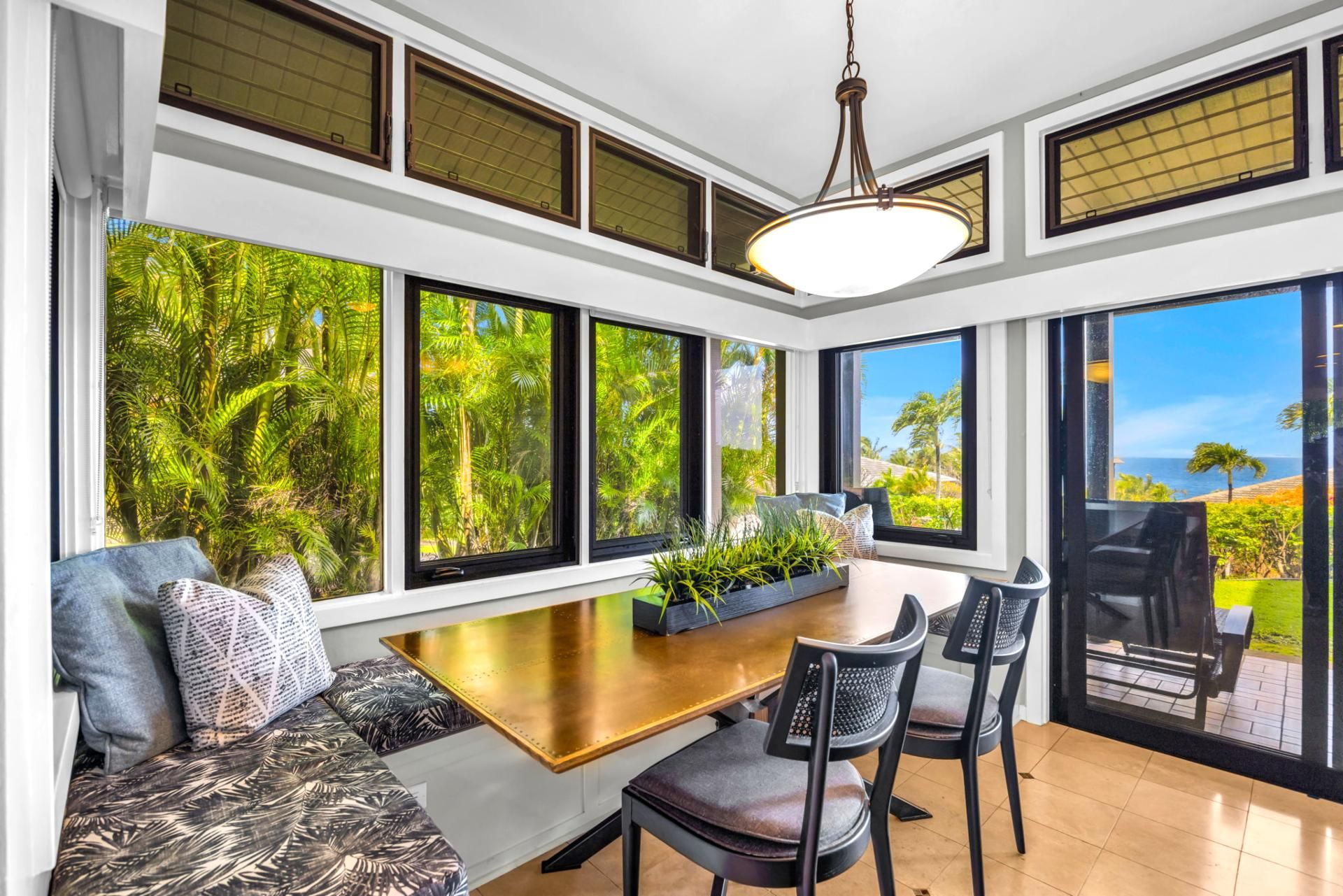 A modern kitchen with large windows, a dining area, and a view of the outdoors.