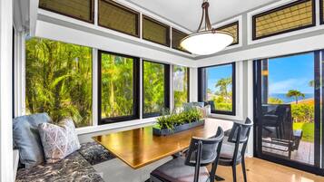 A modern kitchen with large windows, a dining area, and a view of the outdoors.