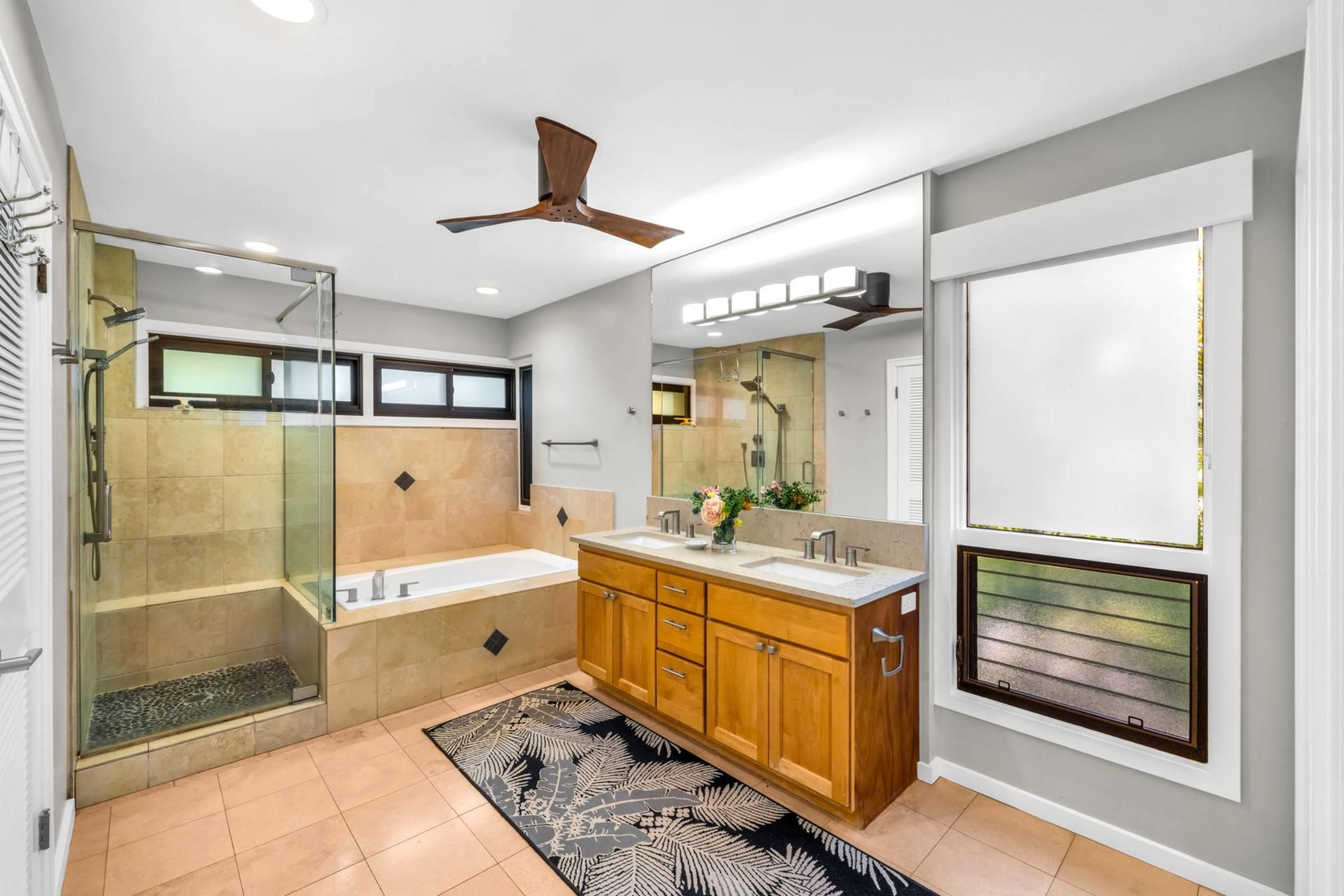 A modern bathroom with a glass-enclosed shower, a bathtub, wooden cabinets, and a large mirror.
