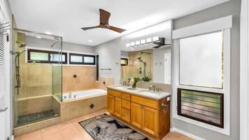 A modern bathroom with a glass-enclosed shower, a bathtub, wooden cabinets, and a large mirror.
