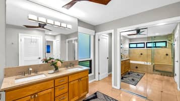 A modern bathroom with a dual sink vanity, a ceiling fan, and a glass shower enclosure.
