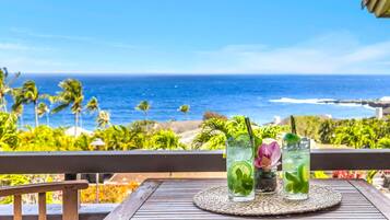 Ein Tisch mit zwei Getränken auf einem Balkon mit Blick auf das Meer.