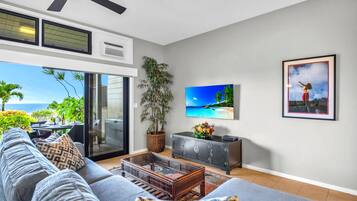 A living room with a sofa, a coffee table, a TV, a cabinet, and a plant.