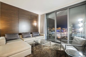 A modern living room with a sofa, armchairs, a glass coffee table, and a large window offering a city view. - Strip View Studio • Balcony • No Resort Fee • Free Parking • TC9 (Las Vegas)