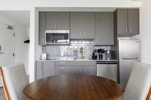 A modern kitchen with grey cabinets, a stainless steel refrigerator, a microwave, and a dishwasher. - Landing | Stylish Studio, Courtyard, Gym (Golden Gate)
