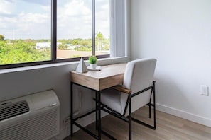 A room with a desk, chair, and a view of greenery outside. - Landing | Stylish Studio, Courtyard, Gym (Golden Gate)