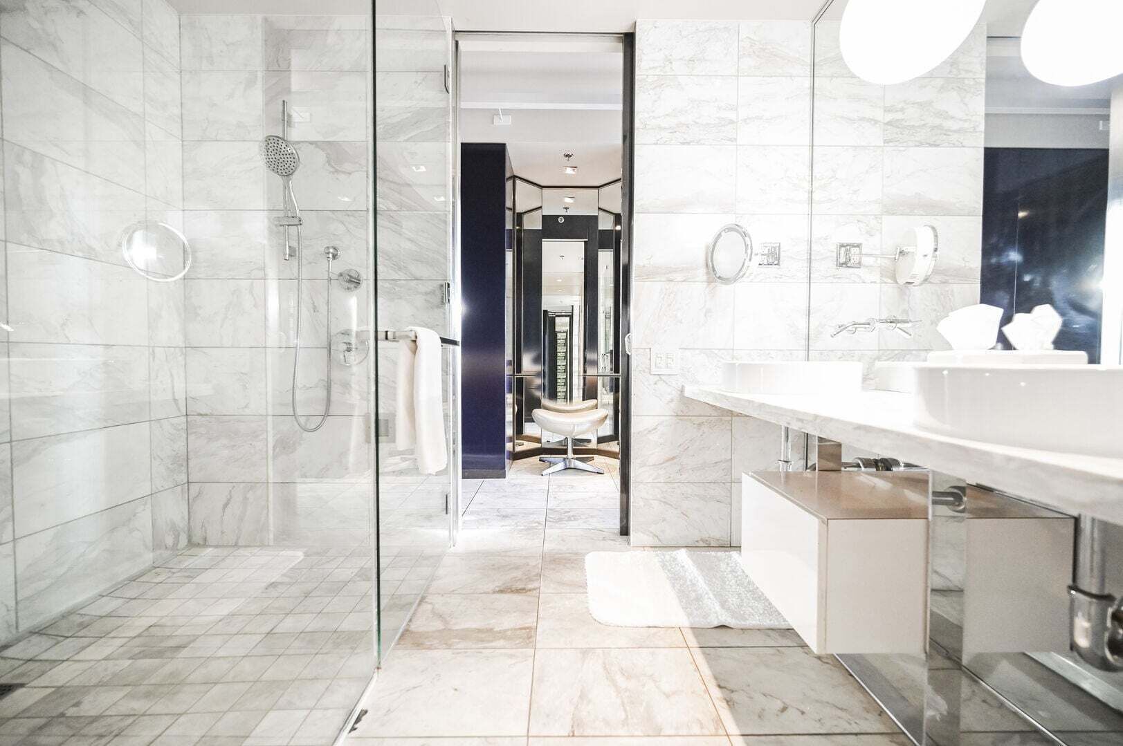 Ein modernes Badezimmer mit einer gläsernen Dusche, einem großen Spiegel und einem Waschtisch.