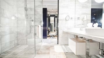 Ein modernes Badezimmer mit einer gläsernen Dusche, einem großen Spiegel und einem Waschtisch.