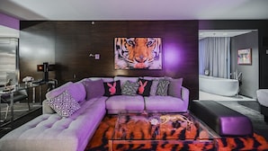Ein modernes Wohnzimmer mit einem Ecksofa, einem Glastisch und einem großen Tigerbild an der Wand.