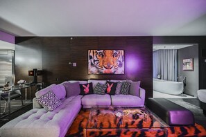 A modern living room with a sectional sofa, a glass coffee table, and a large tiger painting on the wall. - SVS: Tiger-Themed Remodeled 1BD | Strip View Balcony | Palms Place (Las Vegas)
