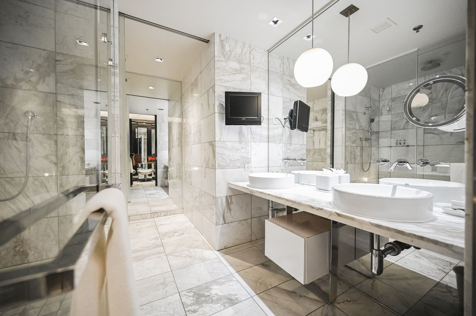 Ein modernes Badezimmer mit Marmorböden, einem großen Spiegel und zwei Waschbecken.