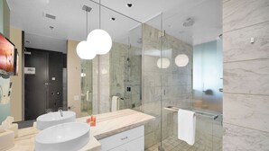 Een moderne badkamer met twee wastafels, een douchecabine van glas en een grote spiegel.