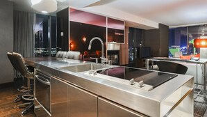 A modern kitchen with a central island, bar stools, and a seating area with a fireplace. - SVS: 1BD Strip View | Jetted Tub | Full Kitchen | Sleeps 4 | Palms Place (Las Vegas)