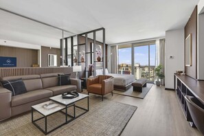 A modern living room with a sofa, armchair, coffee table, and a large window offering a city view. - SVS: Remodeled Strip View Studio | Open Balcony | Resort Pool | Palms Place (Las Vegas)