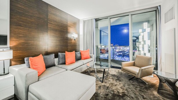 Une chambre d’hôtel moderne avec un canapé, un fauteuil et une table en verre.