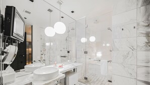 Une salle de bain moderne avec deux lavabos, une douche à l’italienne en verre et un grand miroir.