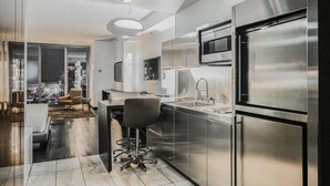 Une cuisine moderne dotée d’appareils électroménagers en acier inoxydable, d’un coin bar et offrant une vue sur la ville.