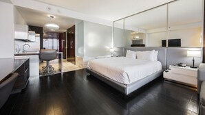 Moderni hotellihuone, jossa on suuri sänky, työpöytä, tuoli, peili ja televisio.