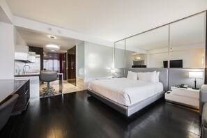 Ein modernes Hotelzimmer mit einem großen Bett, einem Schreibtisch mit Stuhl, einem Spiegel und einem Fernseher.