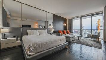 Une chambre d’hôtel moderne dotée d’un grand lit, d’un canapé, d’une table basse et d’un balcon offrant une vue sur la ville.