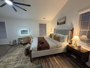 A bedroom with a bed, desk, chair, and a ceiling fan.