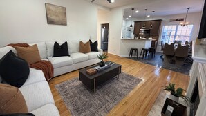 A modern living room with a sofa, coffee table, and a ceiling fan. - GHome, Modern Cozy 5BR 10BEDS located  in Lilburn, GA with AC perfect for family (Lilburn)