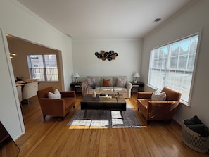 A living room with a sofa, two armchairs, a coffee table, and a rug.