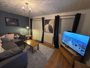 Ein Wohnzimmer mit Sofa, Couchtisch, Fernseher und einem Gemälde an der Wand.