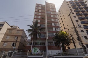 A multi-story building with balconies, a gated entrance, and palm trees. - Apartamento Pet Friendly Beira-Mar no Guilhermina (Praia Grande)